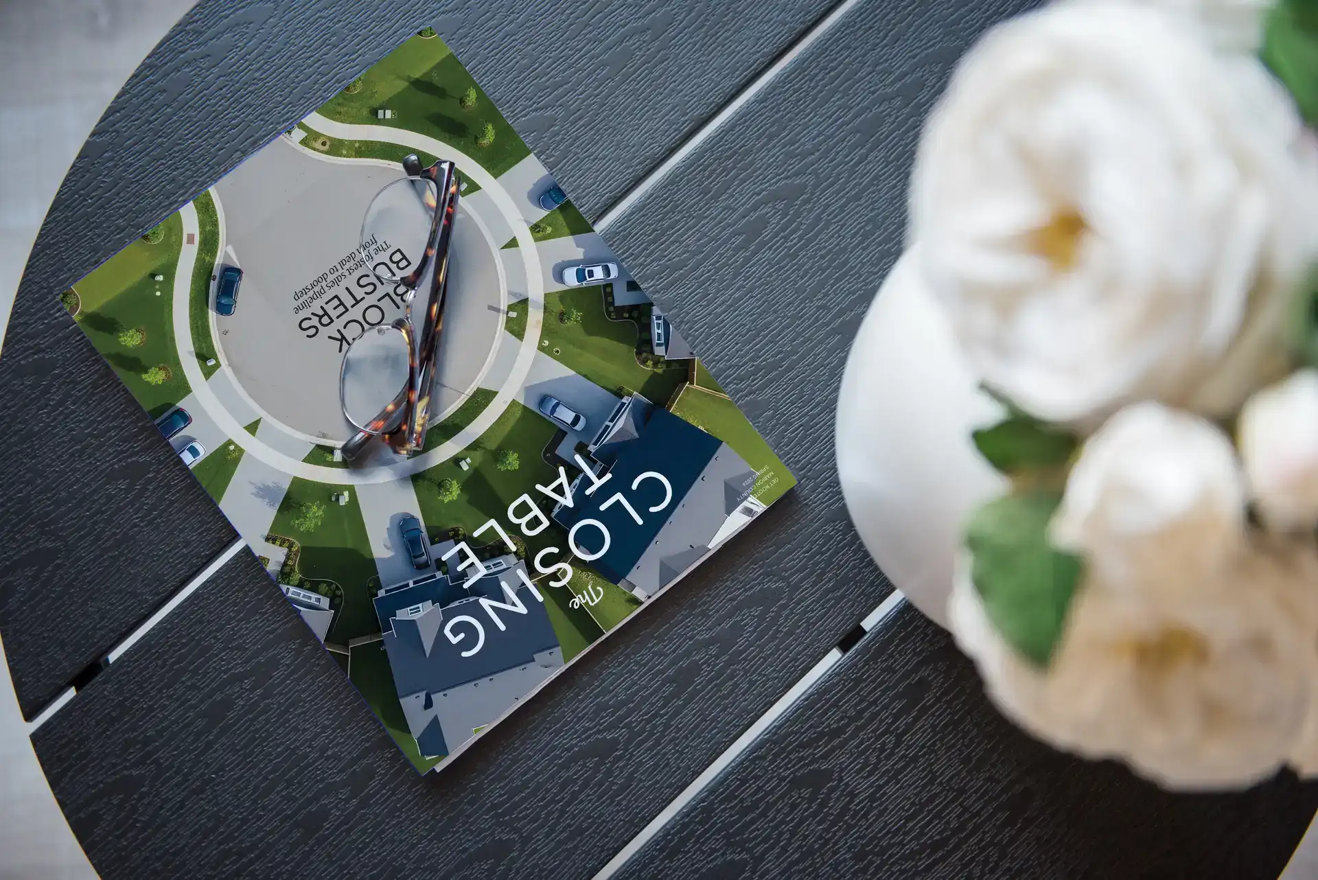 The Closing Table magazine on a dark table with white flowers